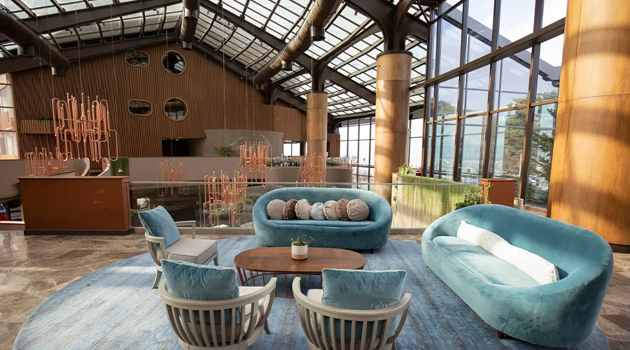 Area lounge di hotel con divani azzurri, poltrone coordinate e tavolino centrale