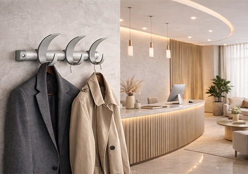 Appendiabiti da parete moderno in metallo con cappotti appesi installato in una reception elegante con bancone curvo e arredi di design.